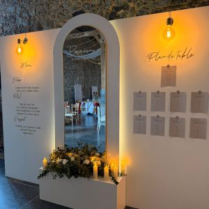 Double panneau blanc avec lampes décoratives pour plan de table avec affichettes et un panneau blanc central sur réhausse avec miroir arrondi et flocage personnalisé